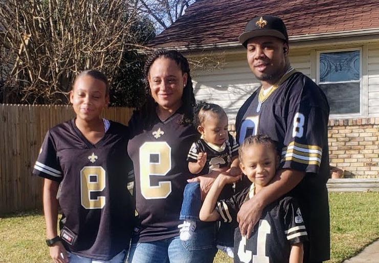 Shametria Turner standing with her family outside a house smiling